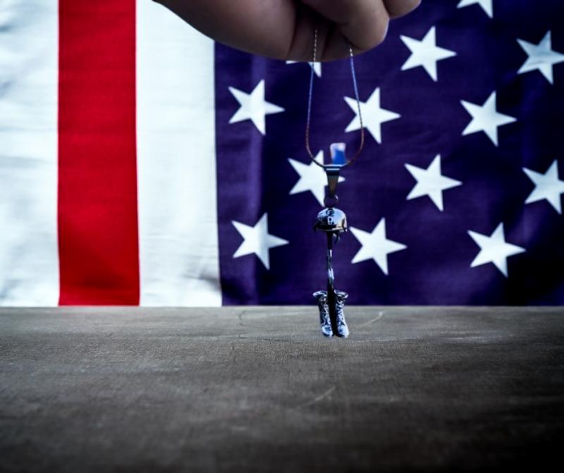 Battle cross pendant urn necklace with American Flag backdrop.