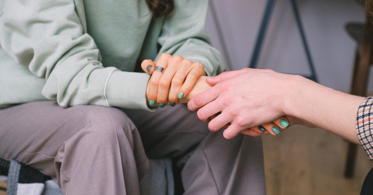 Person holding the hand of another and demonstrating a gesture of sympathy.