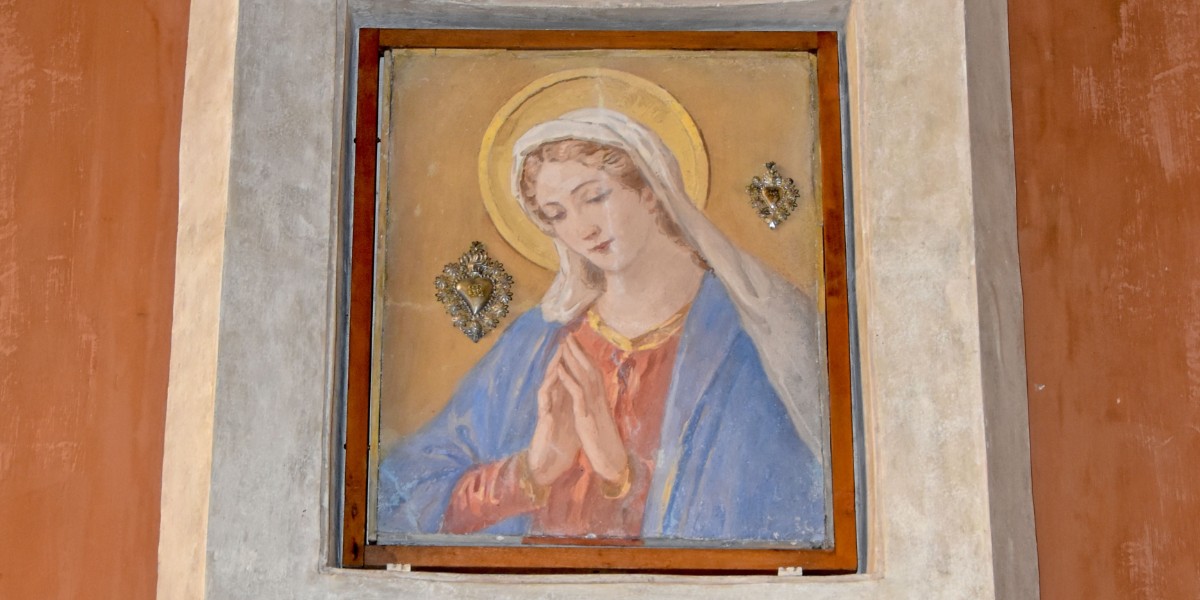 Mother Mary in a blue cape and hood praying.