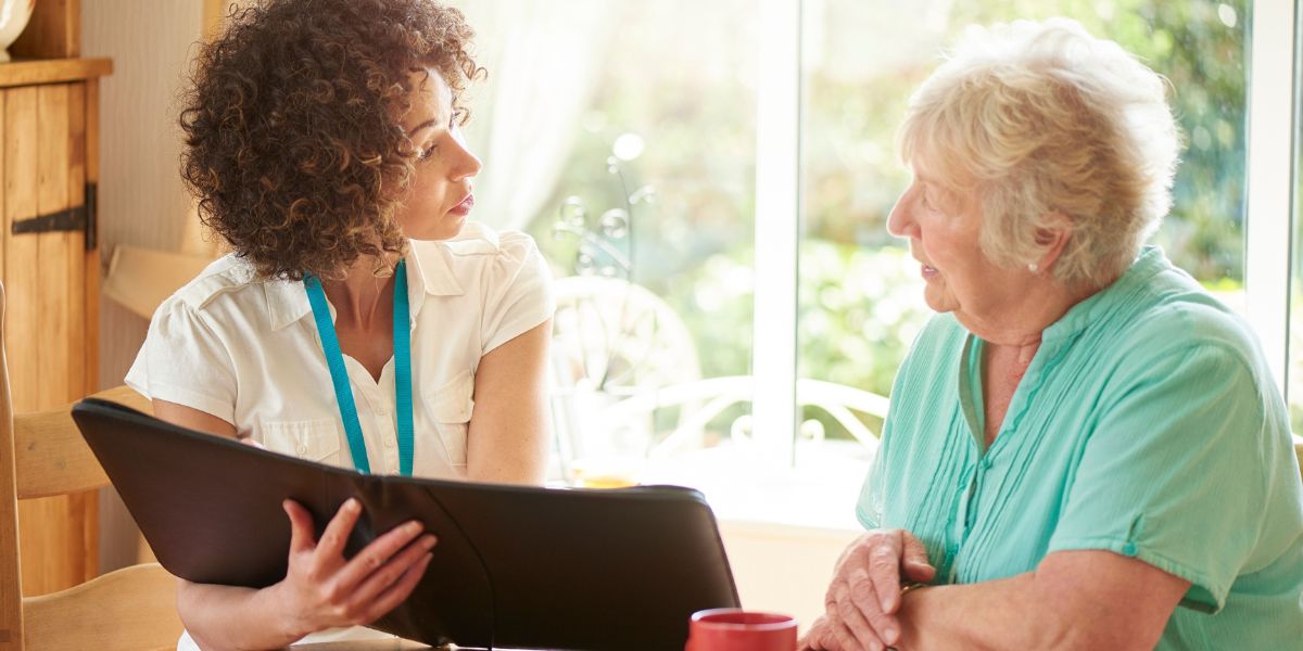 Young woman with black binder presenting funeral costs to an older woman.