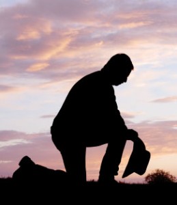Cowboy kneeling holding his hat.