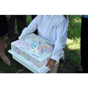 Man holding personalized urn vault with the signatures of friends and family.