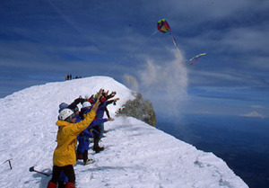 Group of people casting cremated remains on the side of a snow covered hill.