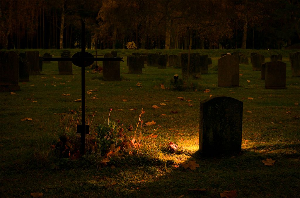 Headstone illuminated by soft light at dusk.