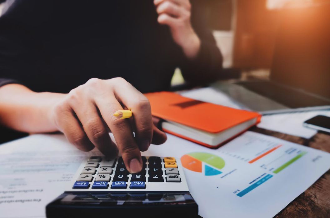 Person calculating budget using a calculator.