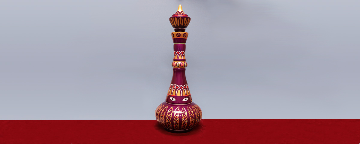 A 3D-printed genie bottle custom cremation urn, painted in violet-red and gold and featuring two black-and-white eyes.