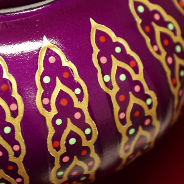 A close-up of the detailing of the genie bottle 3D-printed urn that shows the gold outlining and colorful dots.