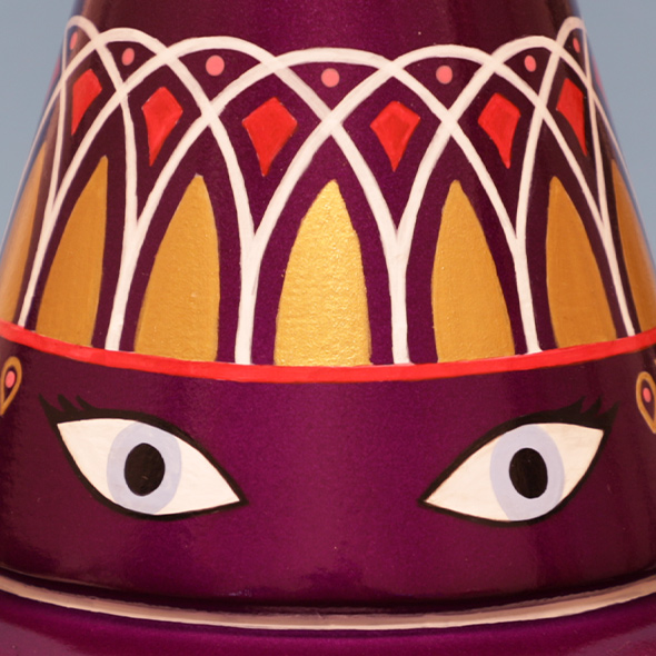 A close-up of the 3D-printed genie bottle custom cremation urn showing two alert eyes painted on the urn with periwinkle irises.