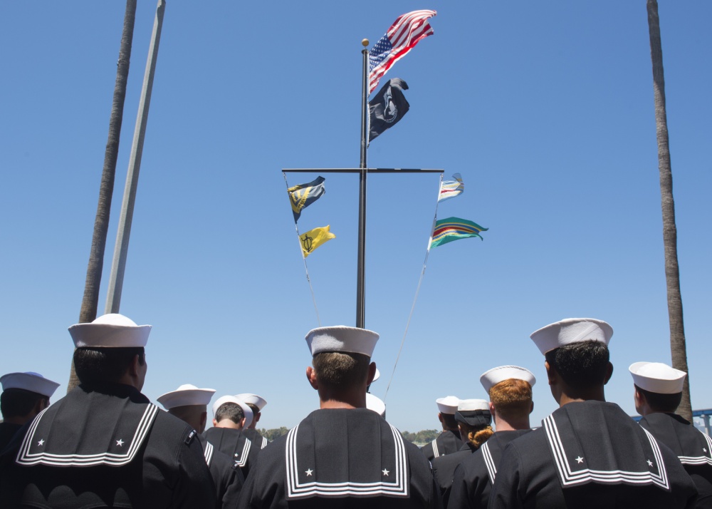 Veterans standing together looking up at country flags.