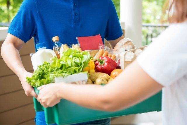 Man delivering a basket of food to a woman.