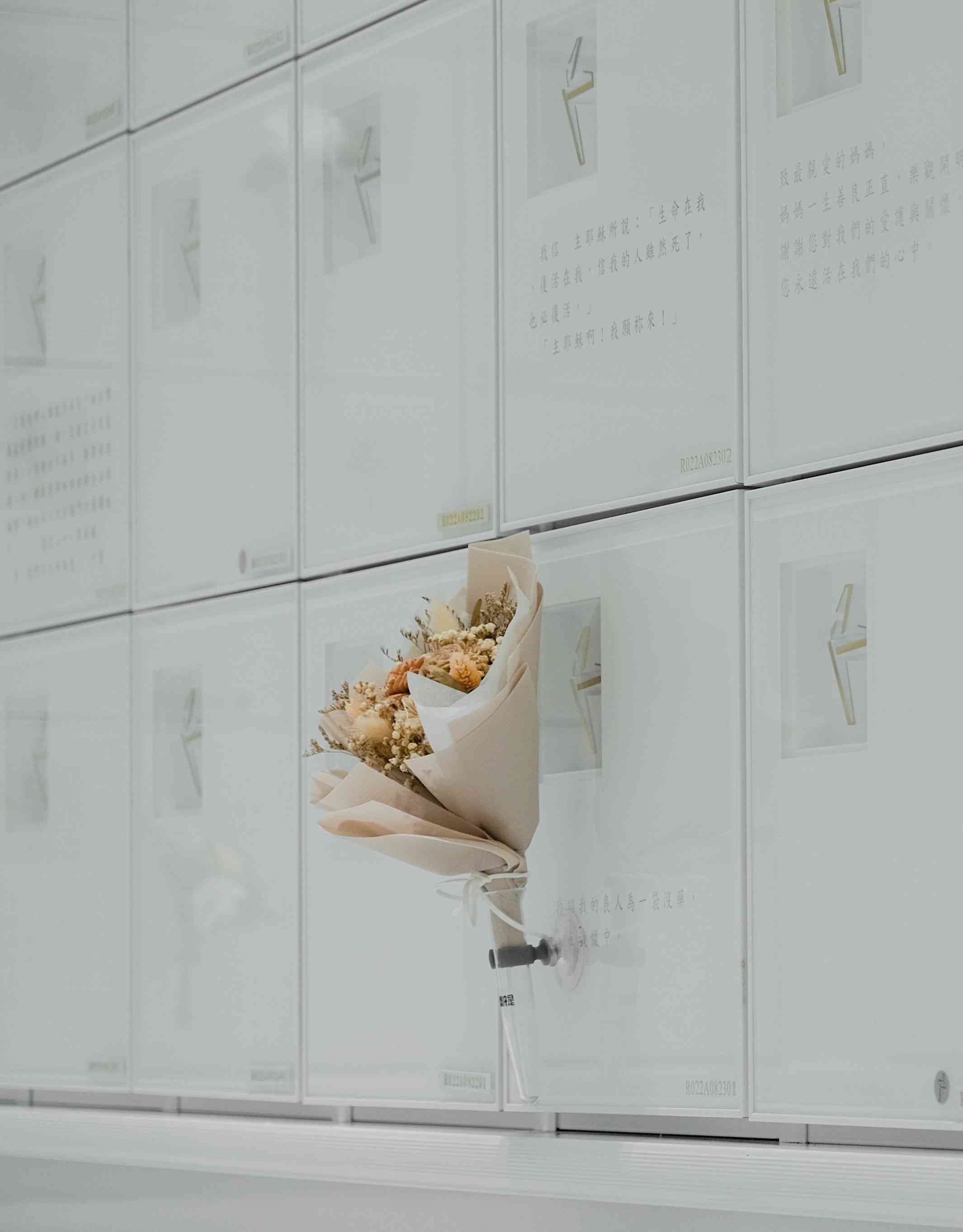 A white marble Columbarium with flowers displayed in front of one niche.