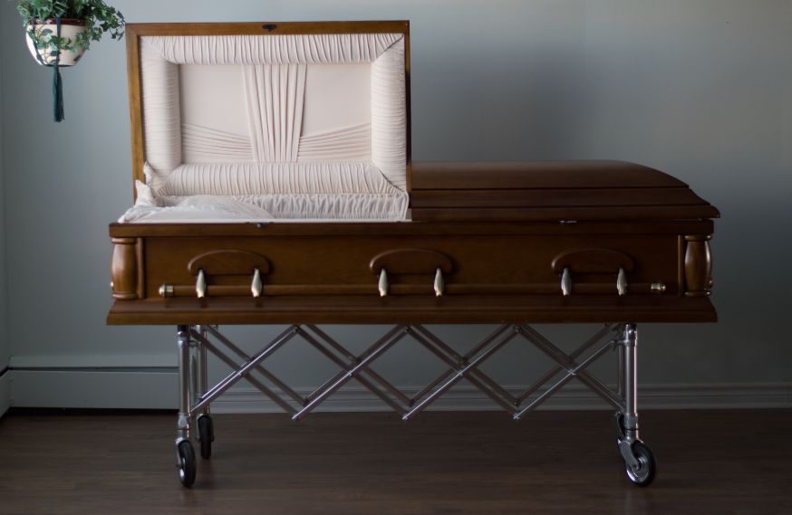 Casket on a stand with the left half of the top open.