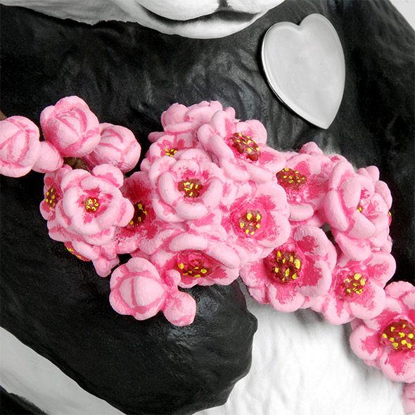 A close-up of the pink cherry blossoms being held by the panda.
