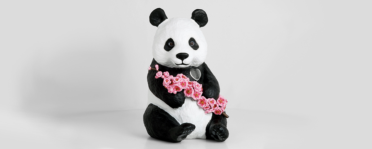 A 3D-printed custom cremation urn that looks like a realistic baby panda sitting upright and holding a branch of cherry blossoms.