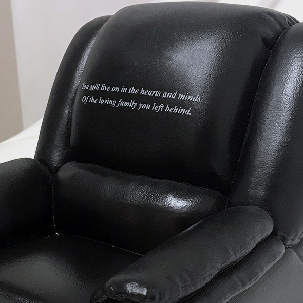An engraving on the 3D-printed recliner keepsake that reads, "You still live on in the hearts and minds of the loving family you left behind."