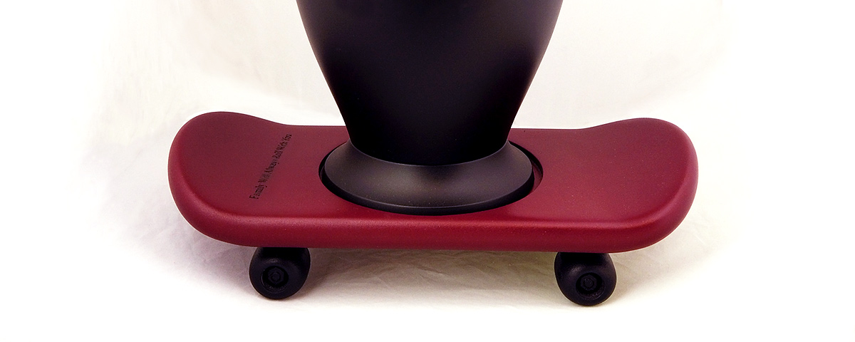 A red 3D-printed skateboard used as an urn base to hold a black urn.