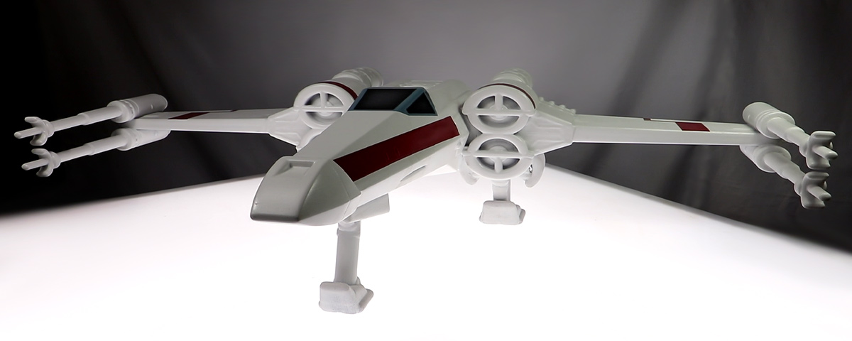 A 3D-printed custom cremation urn resembling an X-wing starfighter from the Star Wars franchise.