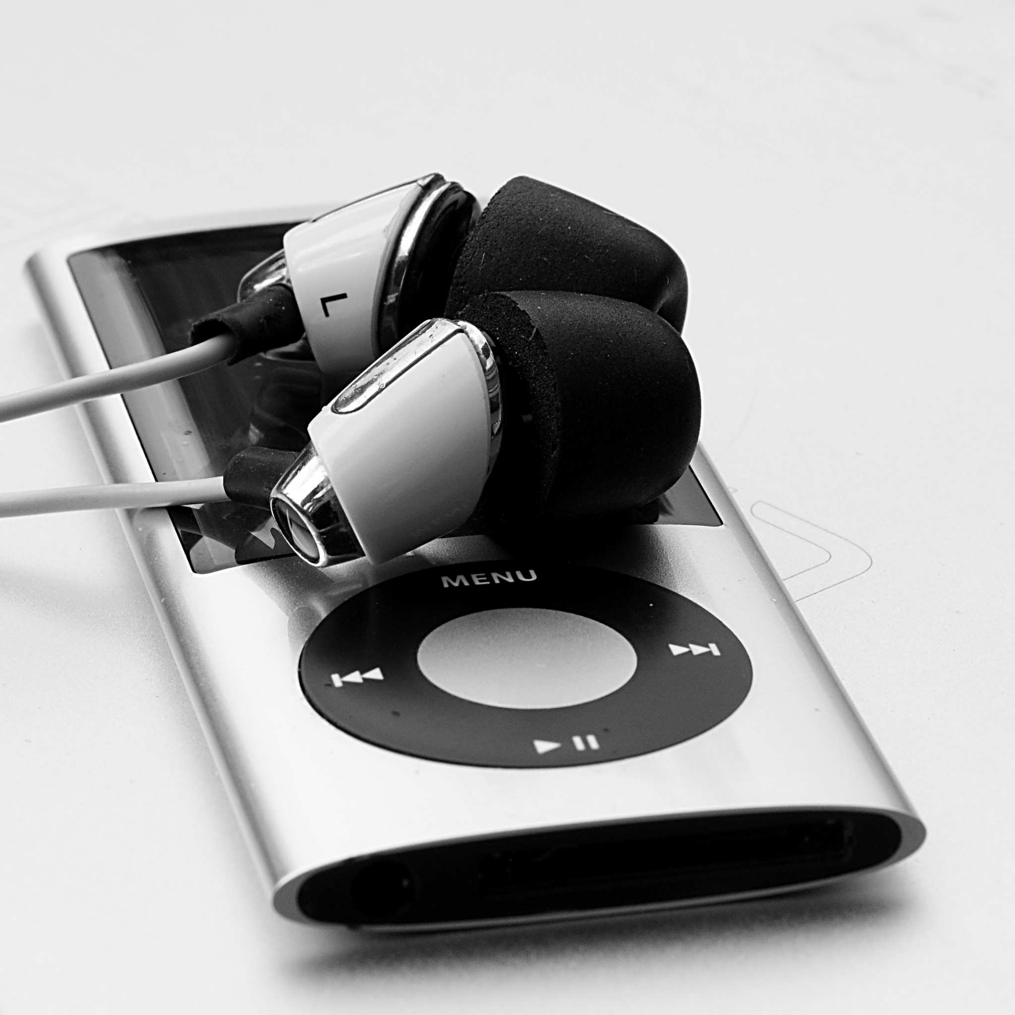 Wired headphones sitting on top of Apple iPod.