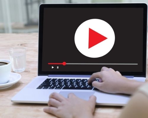 Open laptop with large video play button on the screen.