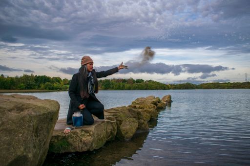 Woman scattering cremation ashes into a lake.