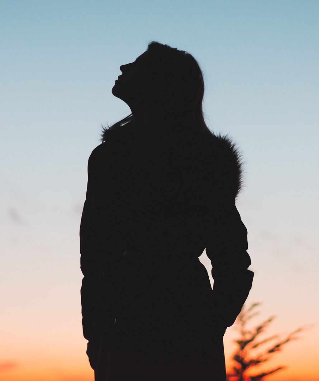Shadow of a woman looking up into the sky at sunset.