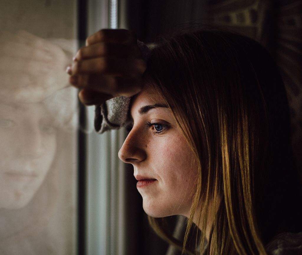 Somber woman looking out the window.