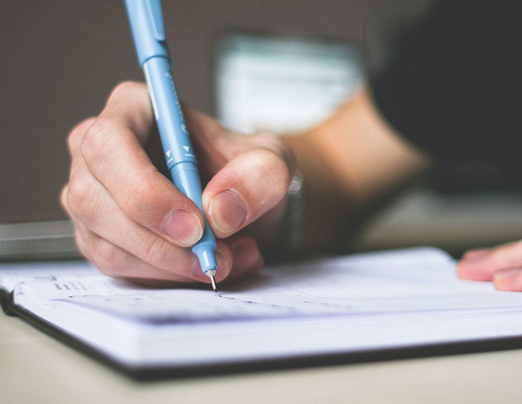 Writing in a journal with a pen.